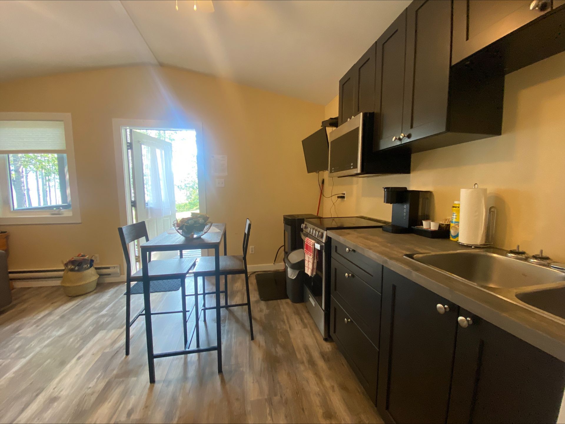 A kitchen with black cabinets , a sink , a stove and a table.