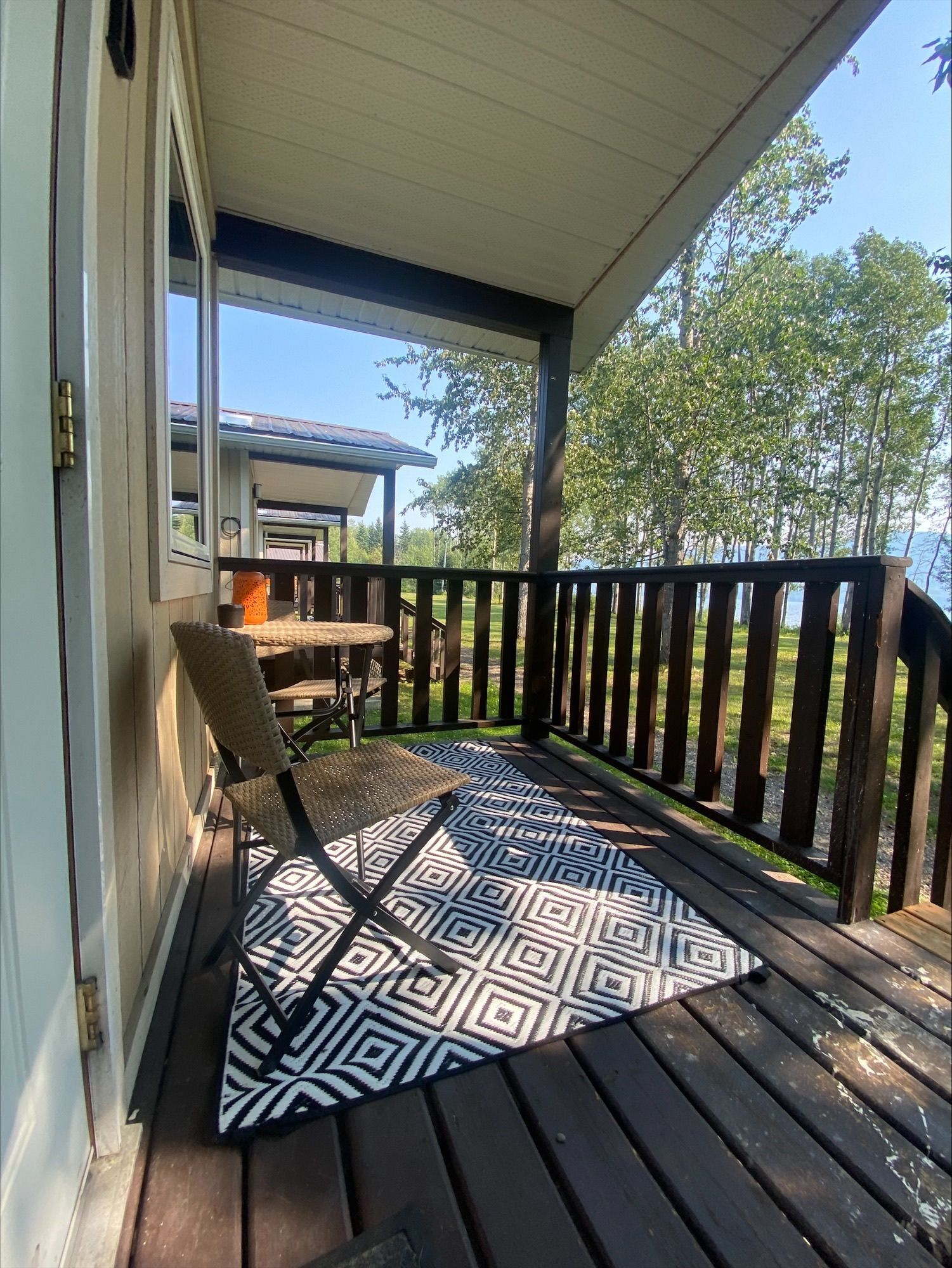 A porch with a chair and a rug on it.