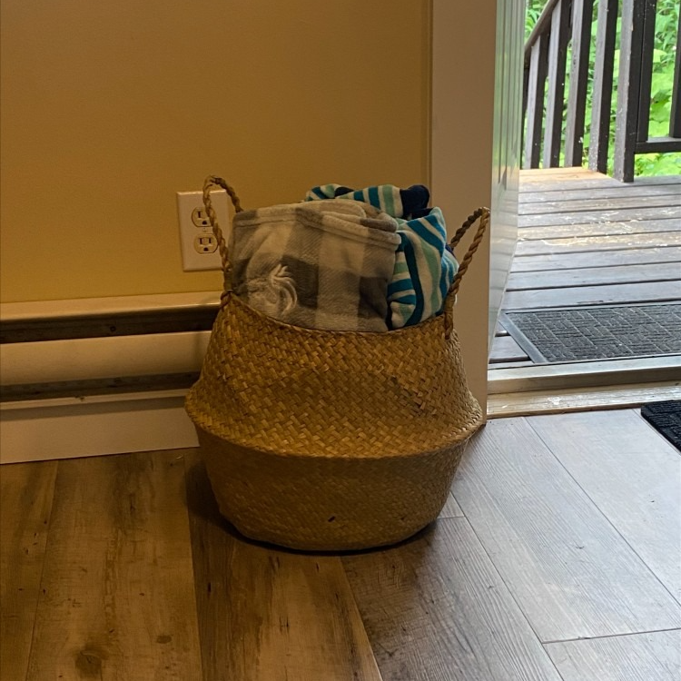 A basket filled with blankets is sitting on a wooden floor