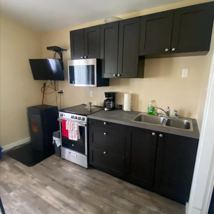 A kitchen with black cabinets and stainless steel appliances