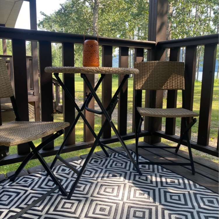 A table and chairs on a porch with a black and white rug