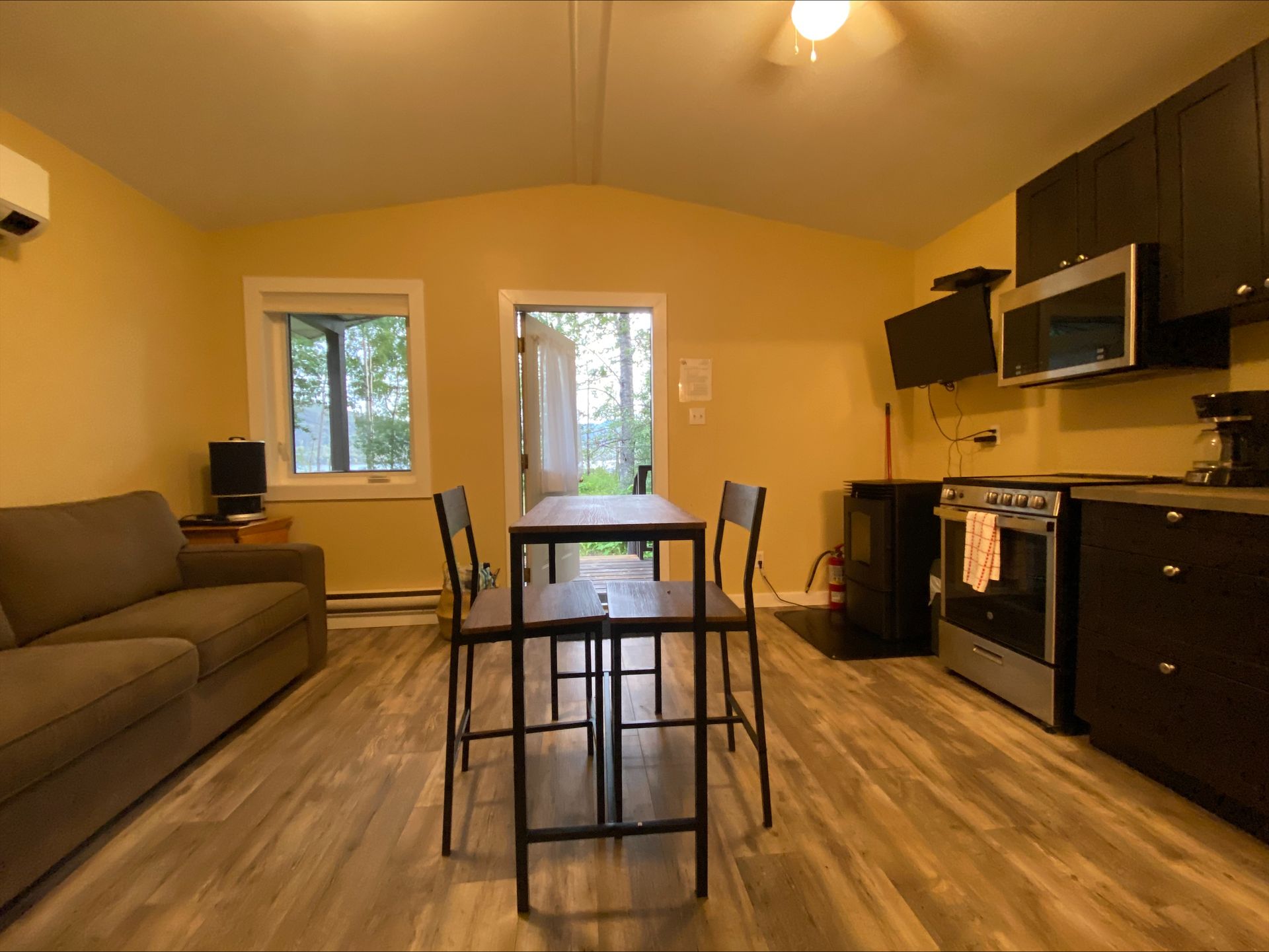 A living room with a couch , table , chairs and a kitchen.