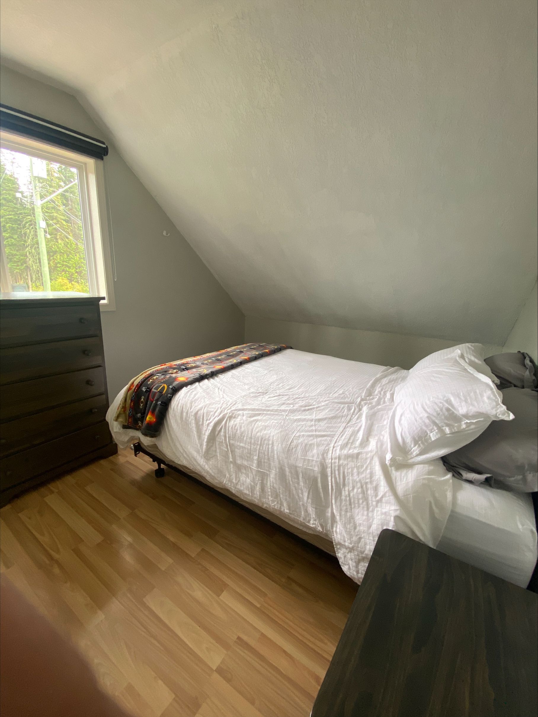 A bedroom with a single bed and a window.