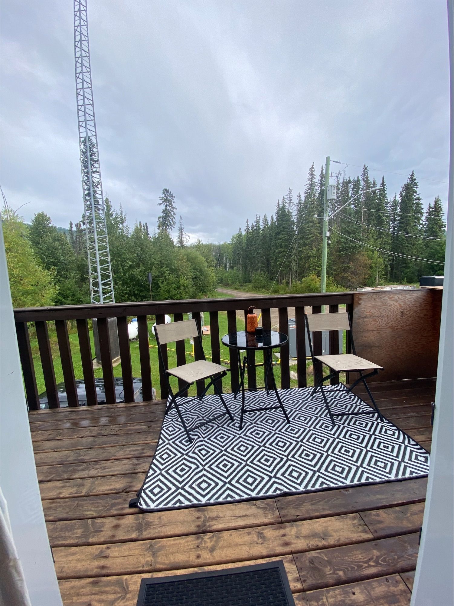 A wooden deck with chairs and a rug on it.