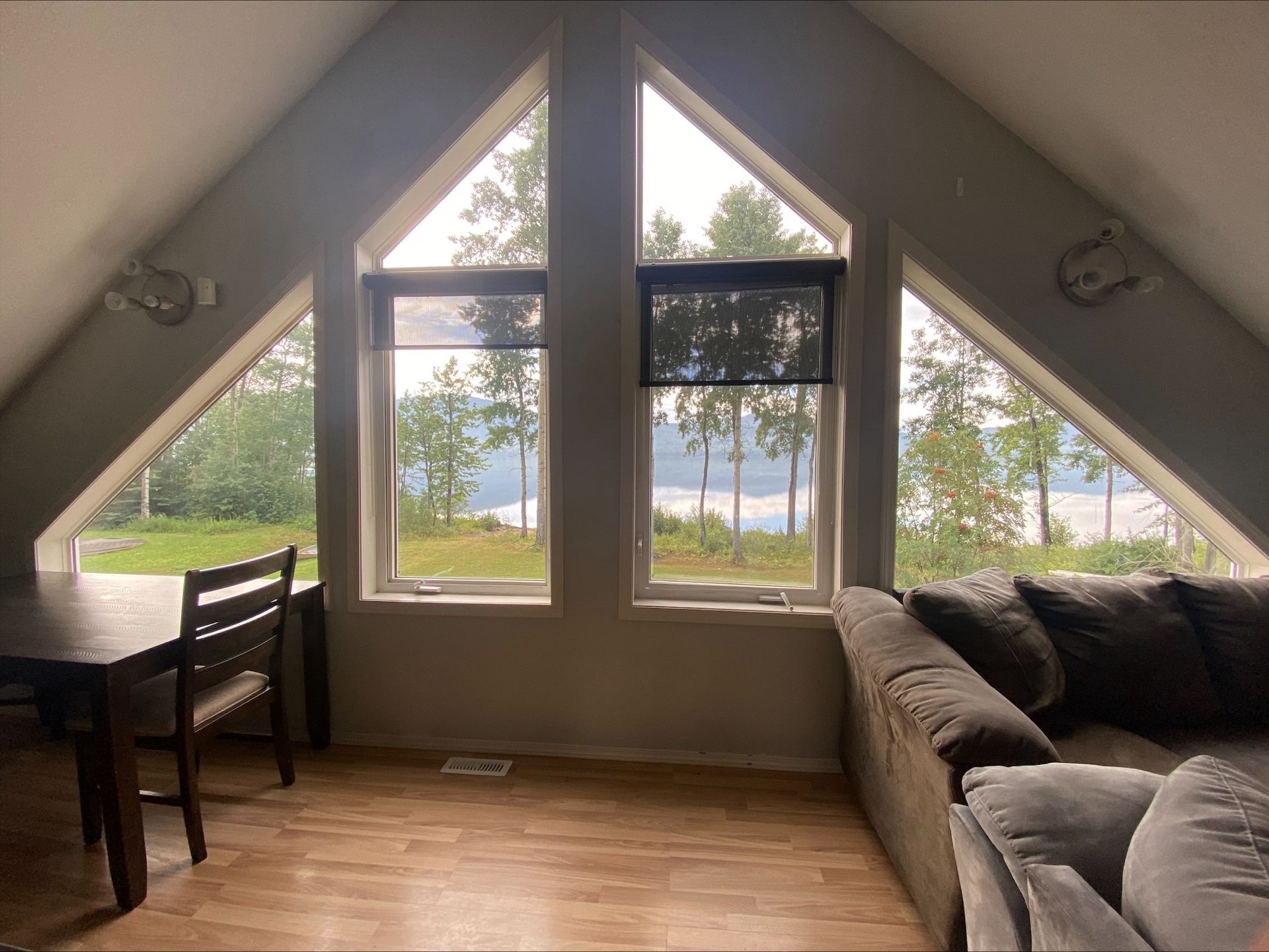 A living room with a couch , table and chairs and a view of a lake.