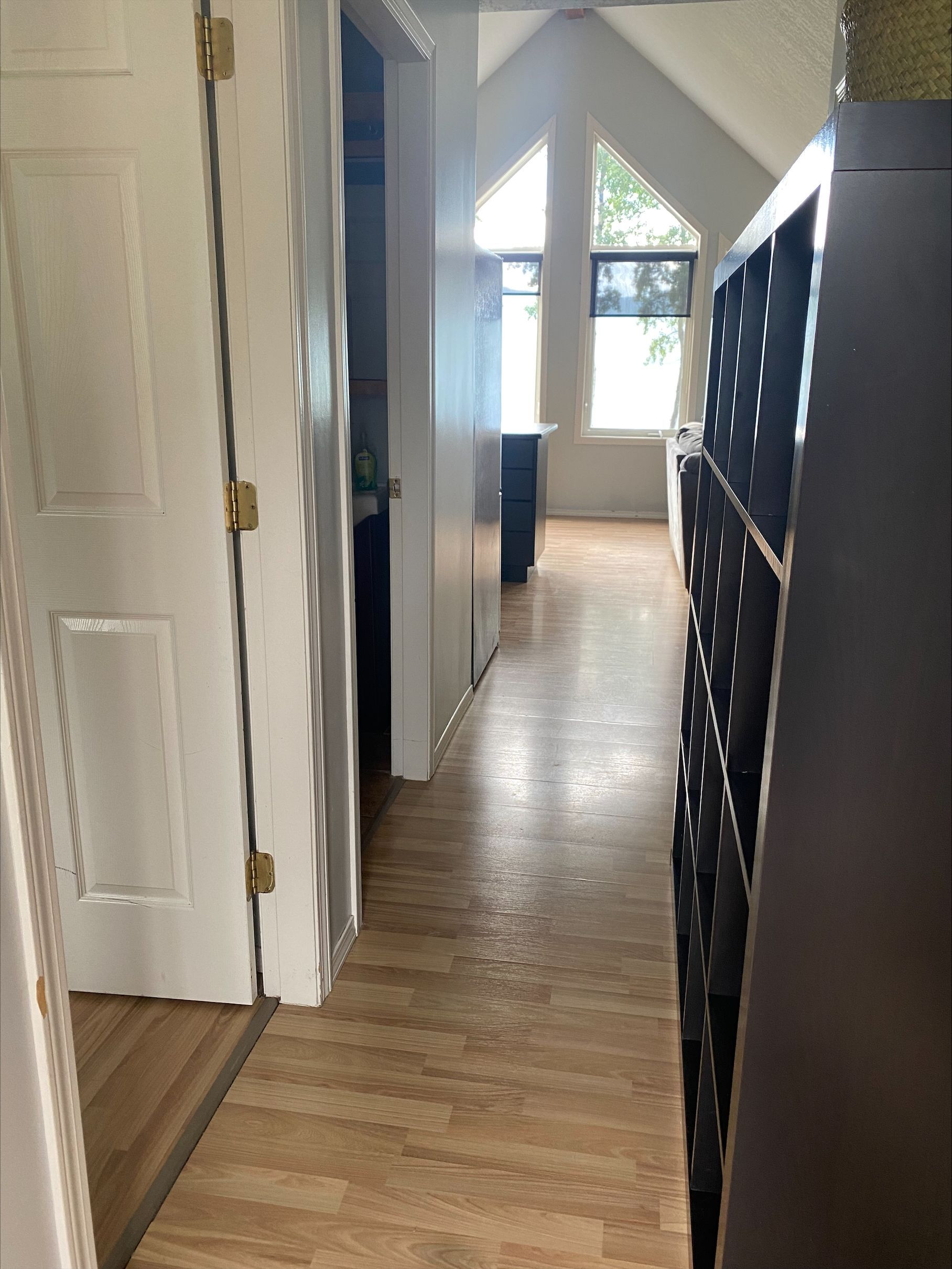 A hallway in a house with hardwood floors and a vaulted ceiling.