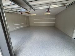 Empty gray garage interior with a speckled floor and overhead door tracks
