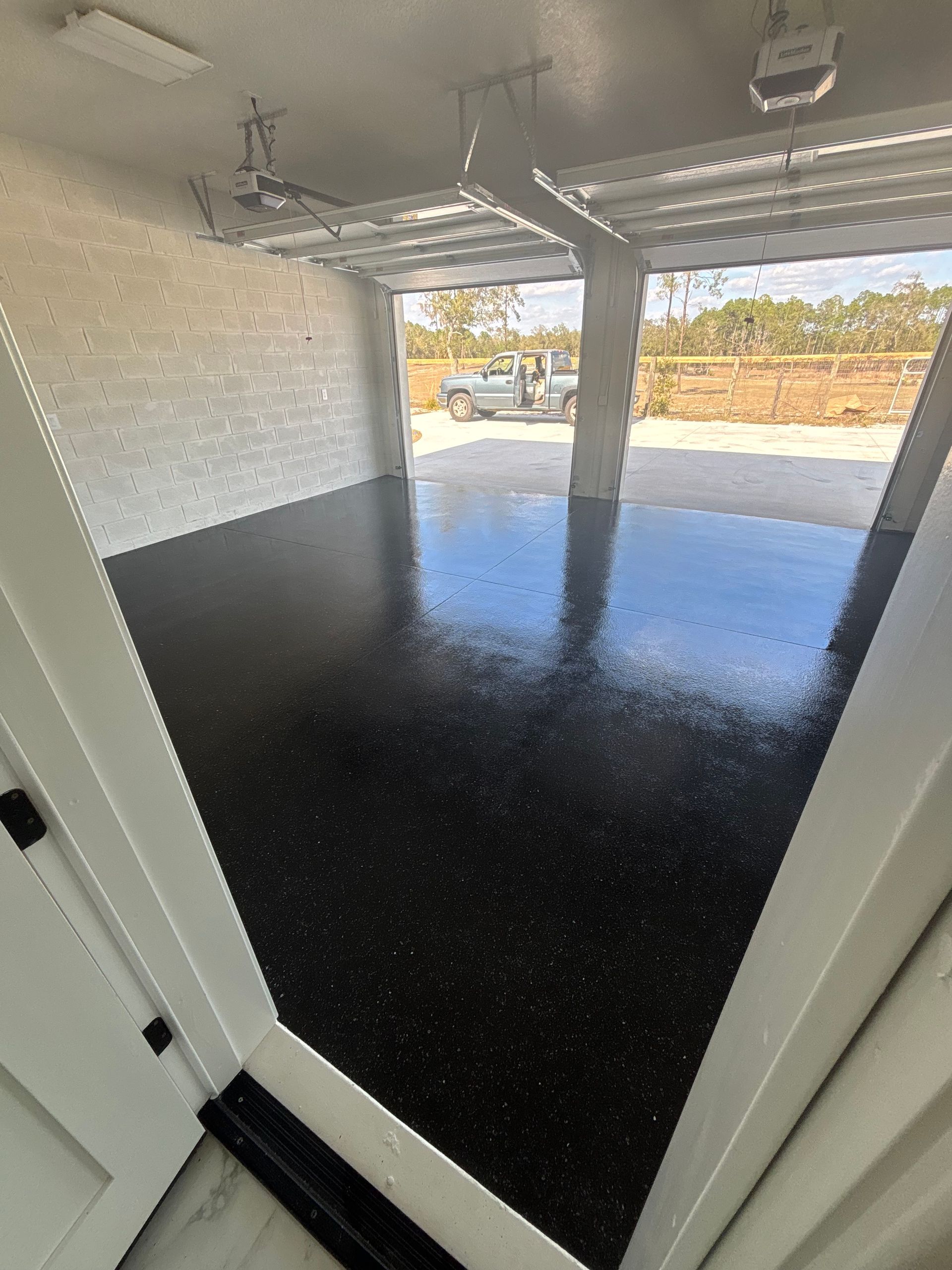 Covered patio with glossy black epoxy floor and open view to a backyard fence