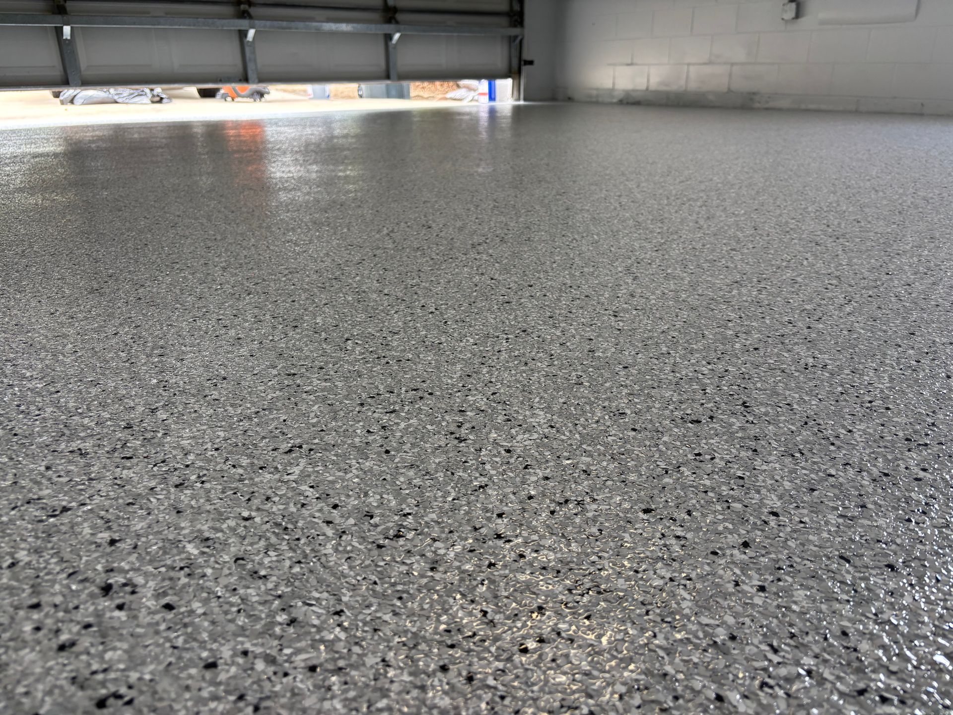 Speckled gray garage floor under a partially open garage door, with light coming in from outside