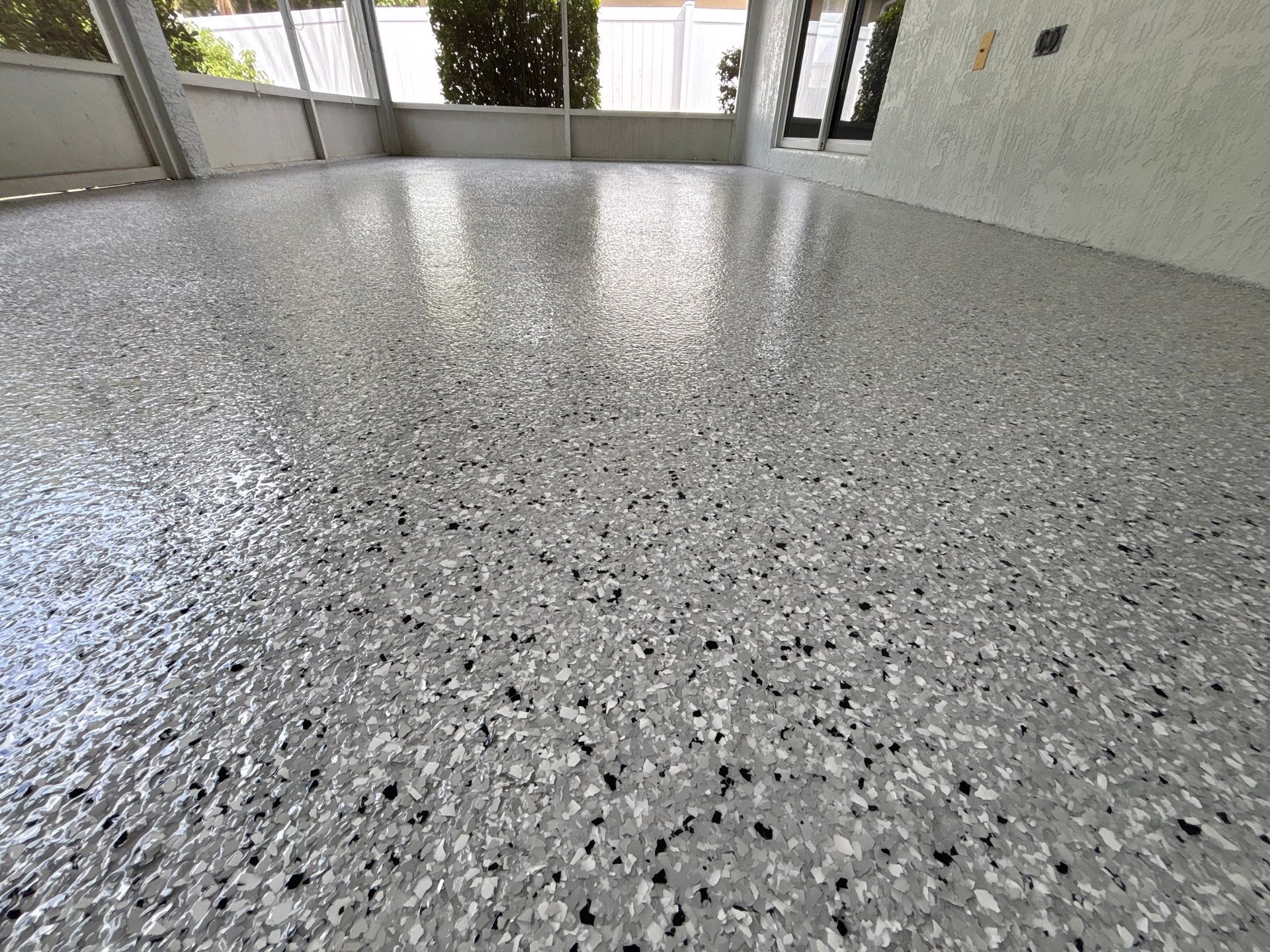 Speckled gray epoxy floor in a bright indoor space with windows and walls on both sides