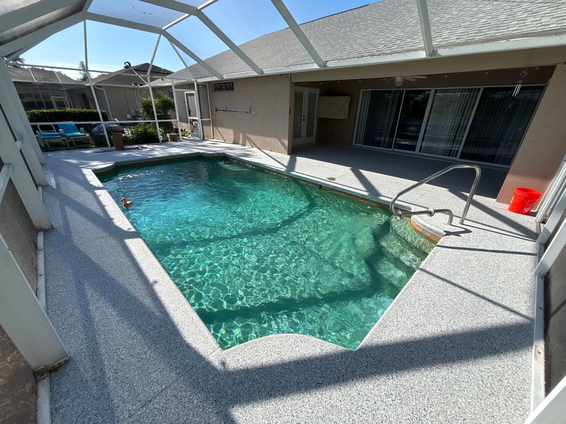 Screened-in backyard pool with turquoise water and patio furniture under a white enclosure