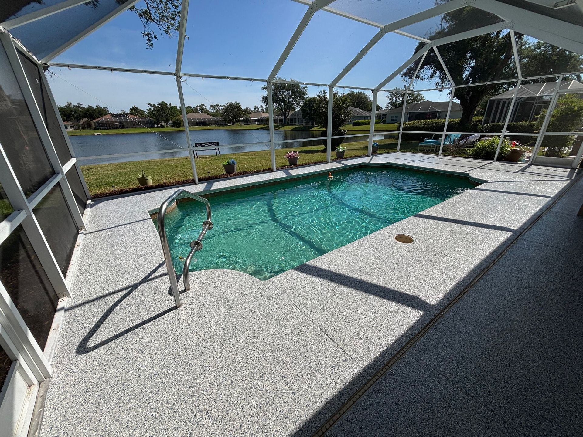 Screened-in backyard pool with blue water and a lake view beyond the patio