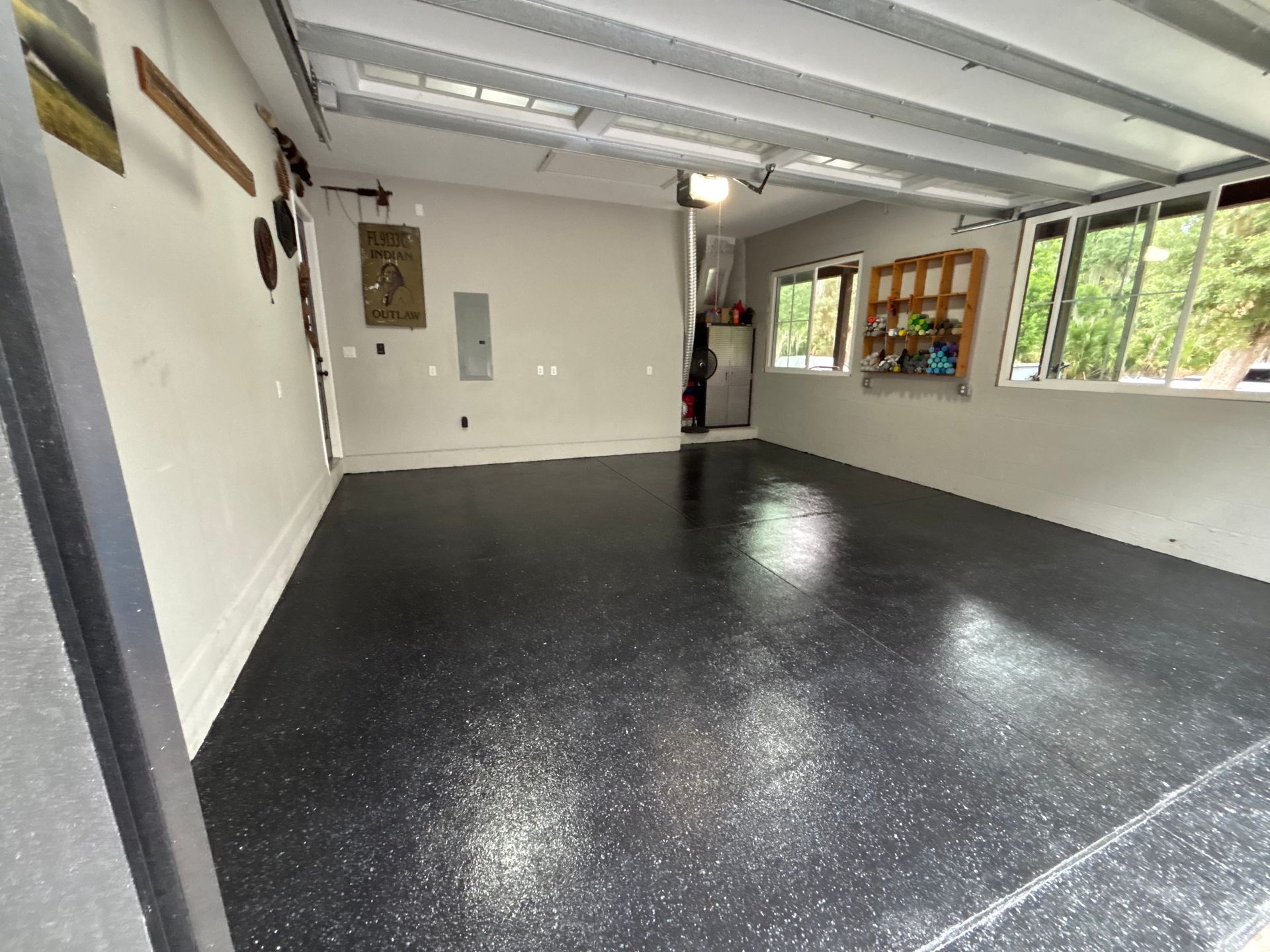 Empty garage with black speckled epoxy floor, white walls, and windows on the right