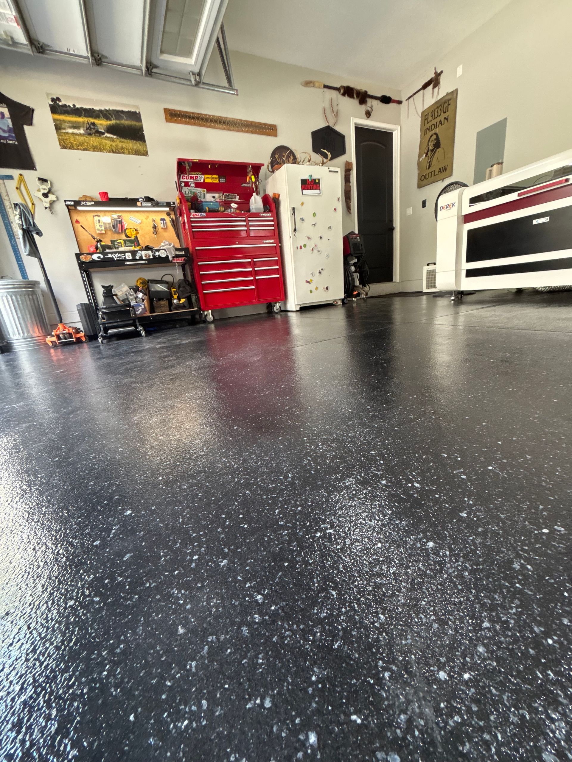 Spacious garage with speckled black floor, red tool chest, workbench, and car lift visible.