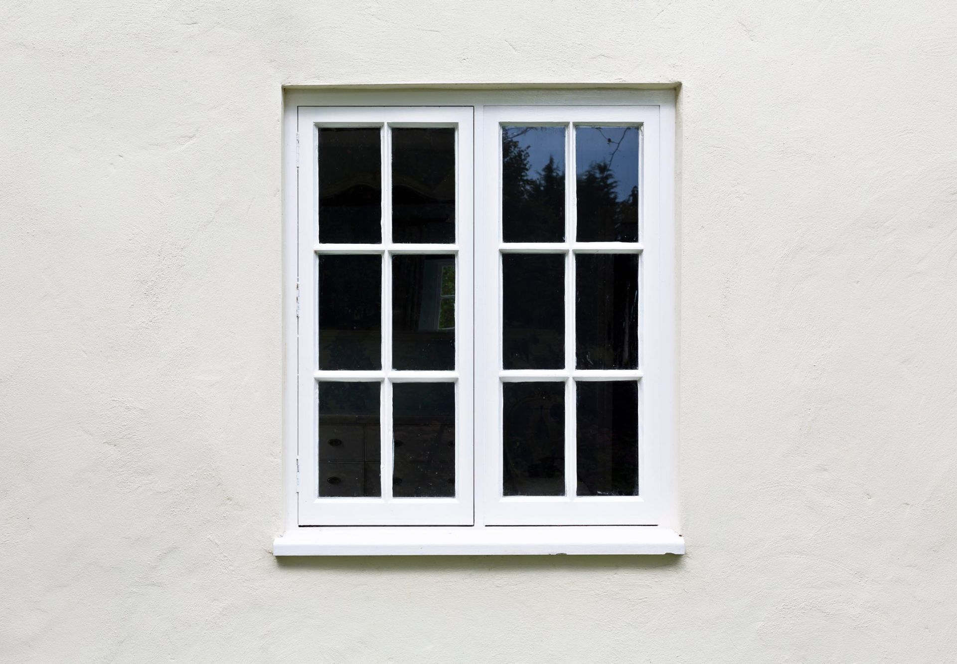 A white window is on the side of a building.