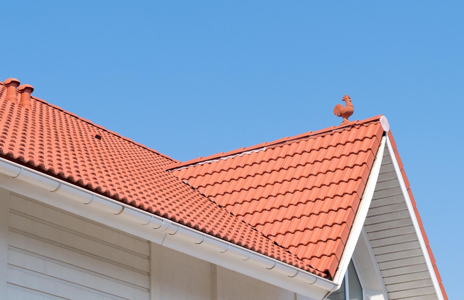 A house with a red tiled roof and a bird on top of it.