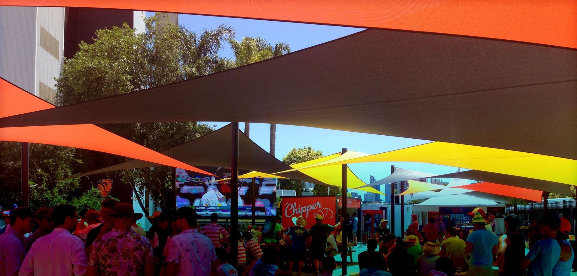 A group of people standing under shades at a party