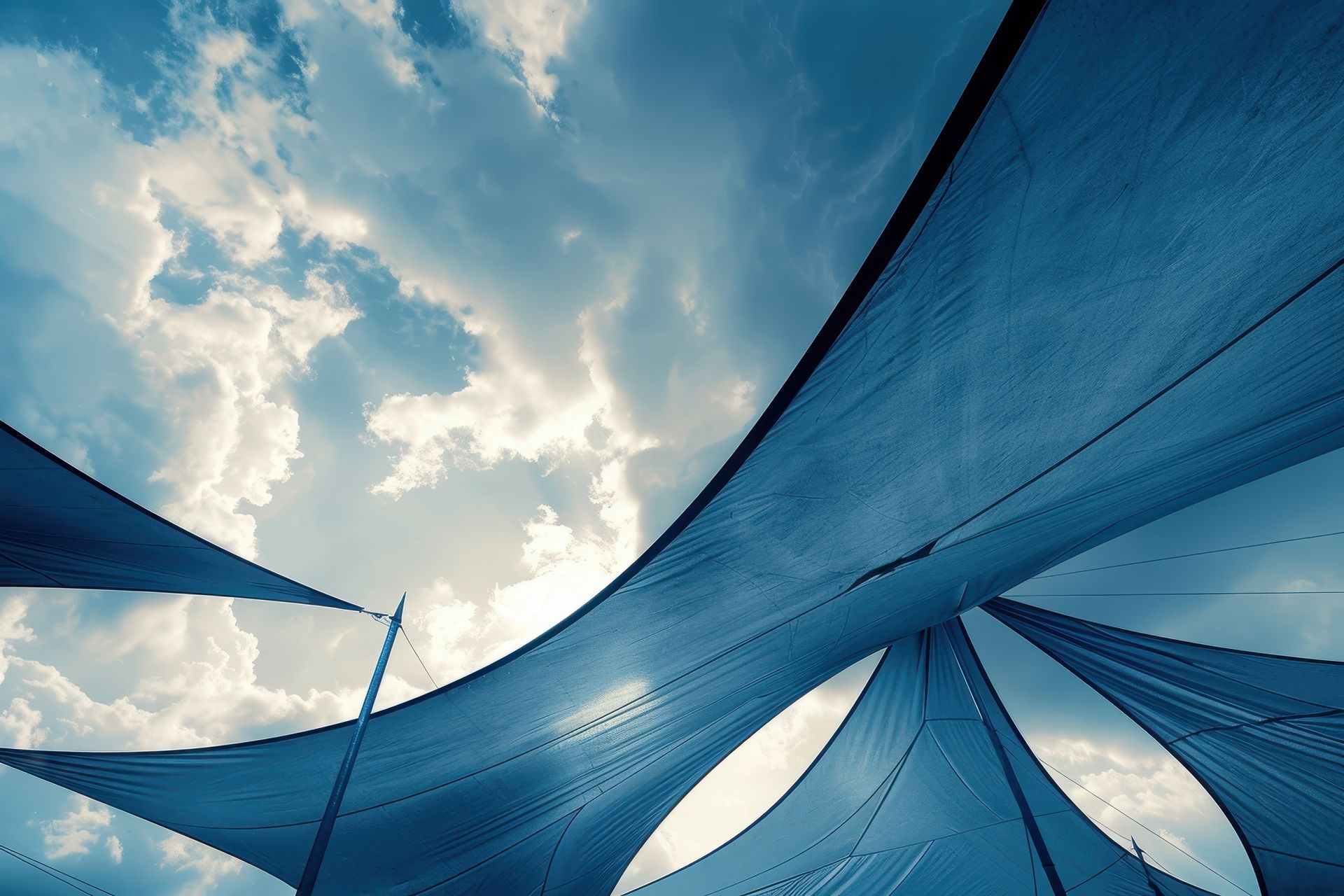 Blue shade sails over outdoor play area against cloudy sky. Blue shade sails over outdoor play area against cloudy sky.
