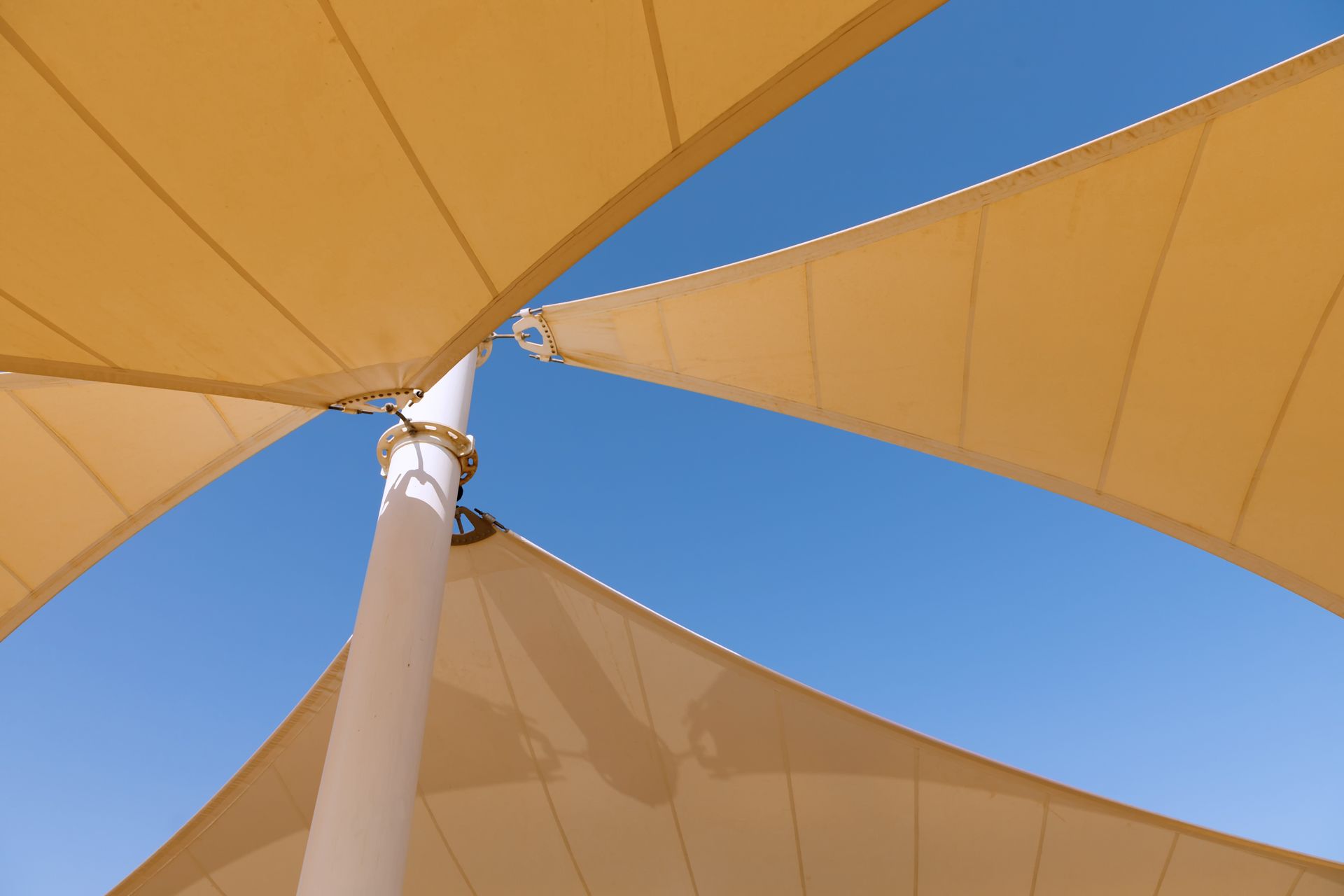 Close-up of yellow shade sail against bright sky. Close-up of yellow shade sail against bright sky.