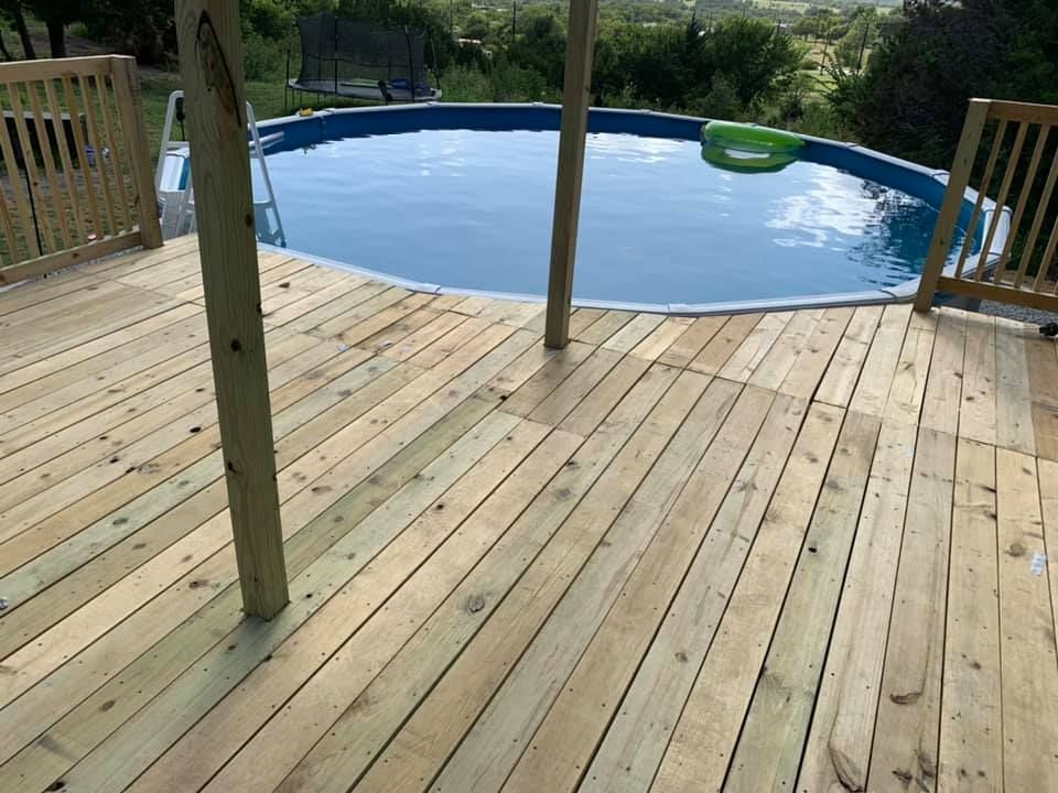 A newly built wooden deck overlooking a circular above-ground pool in a grassy backyard.