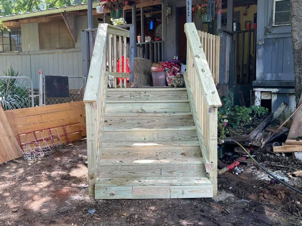 Newly constructed wooden stairs with handrails leading up to the front entrance of a house.