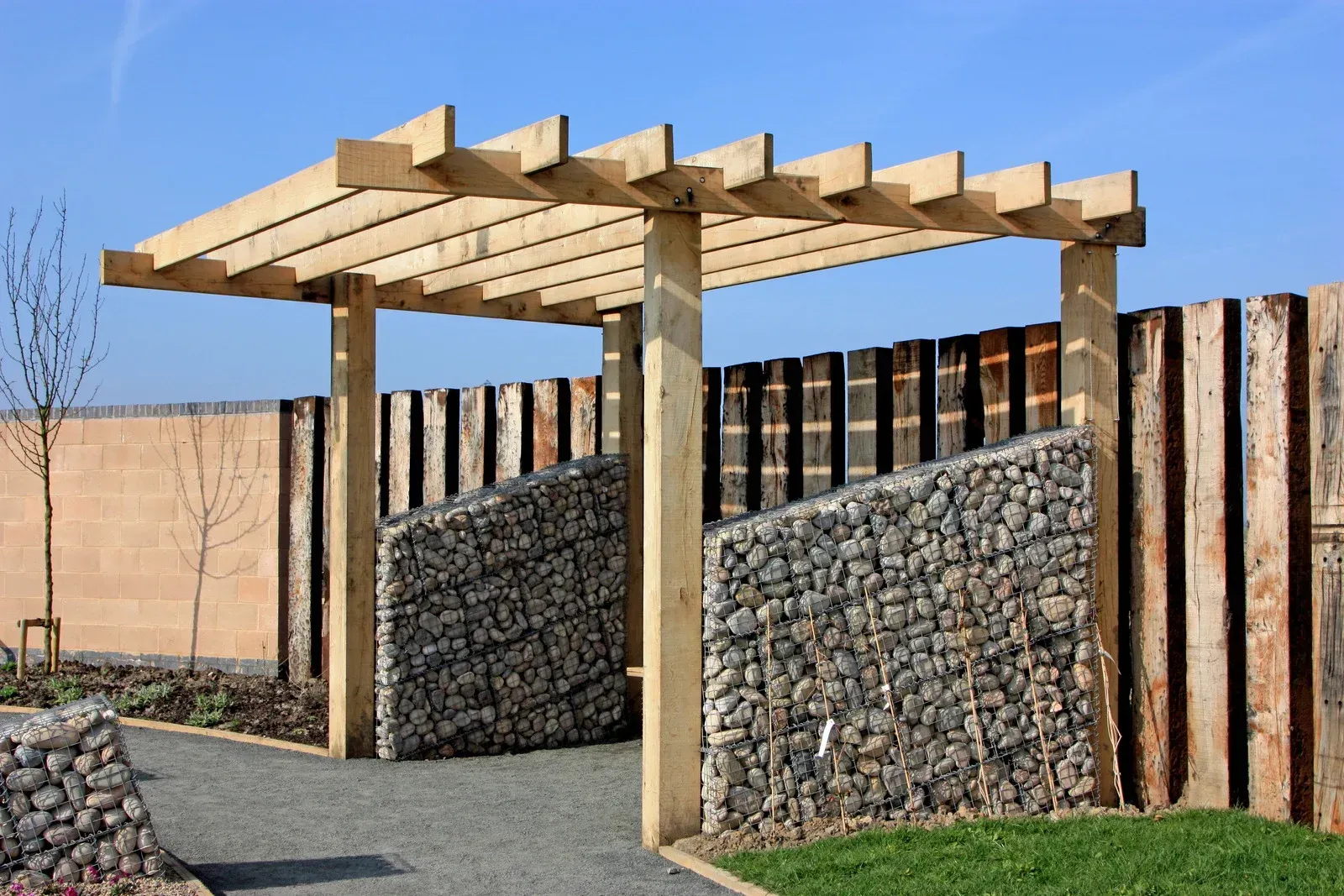 A covered outdoor patio featuring a natural wood-plank ceiling supported by wooden beams attached to a brick wall.
