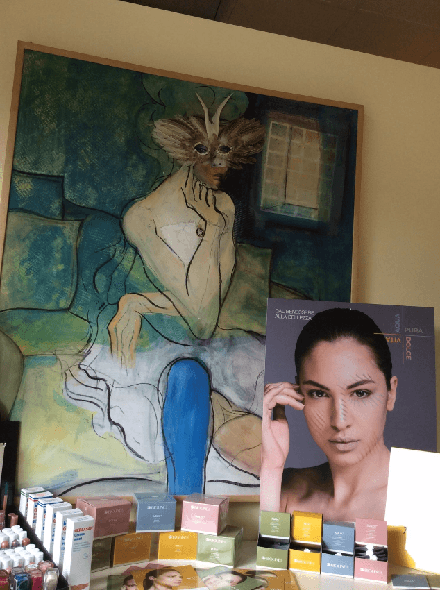 Sopra l'espositore dei cosmetici è dipinto un murale, con un poster di una modella e piccole scatole di prodotti sottostanti.