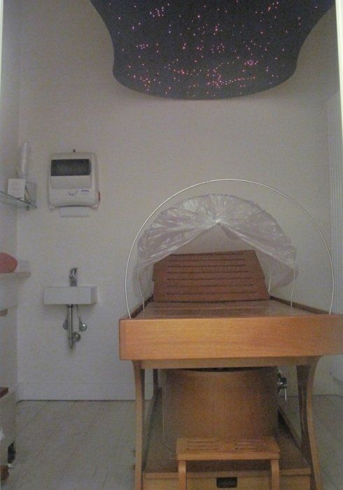Piccola sala per trattamenti con una sedia di legno ricoperta di plastica sotto una lampada a soffitto che simula un cielo stellato.