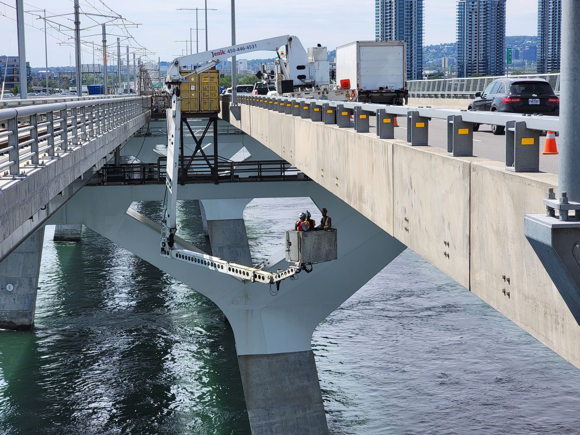Pont routier enjambant l'eau, soutenu par une structure triangulaire temporaire, près du rivage d'une ville.
