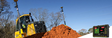 Un bulldozer jaune équipé de deux mâts de levé GPS est posé sur un tas de terre, avec un écran de contrôle numérique affiché à droite.
