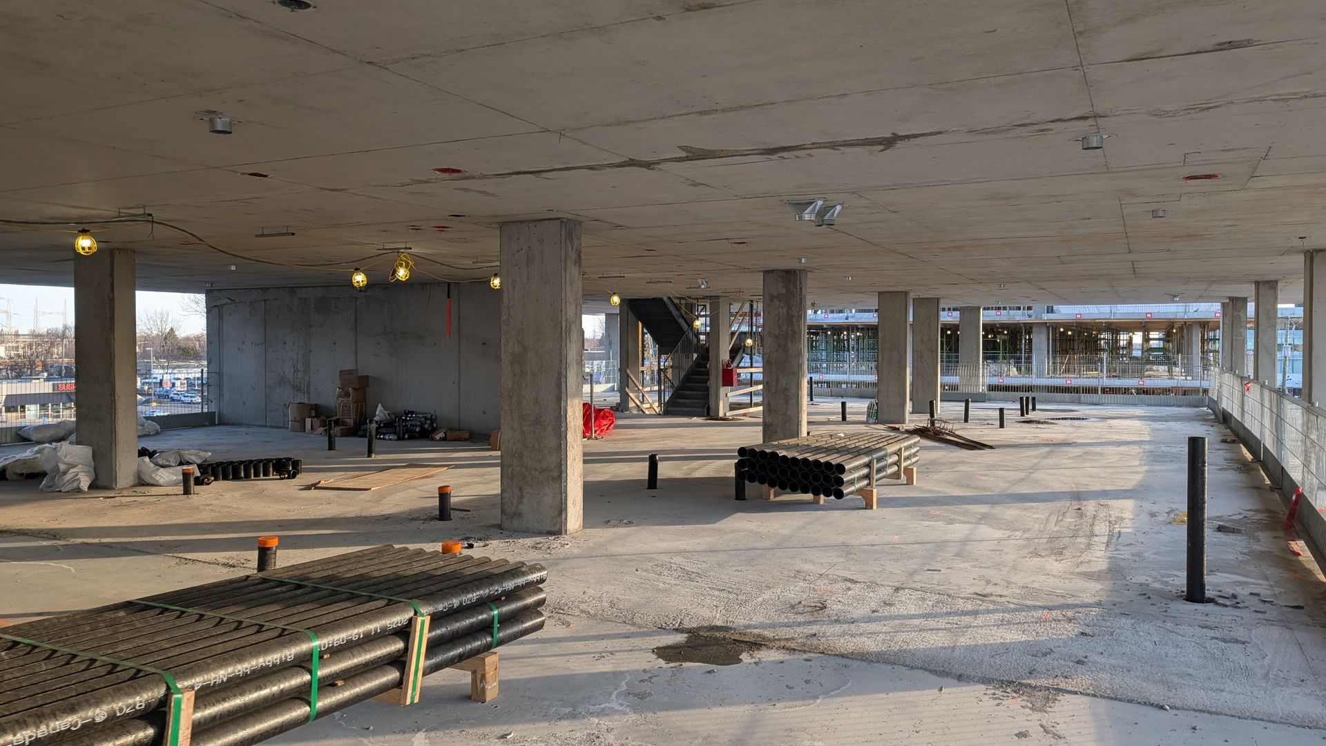 Une structure en béton inachevée, avec des piliers et un sol apparent, sur un chantier de construction.