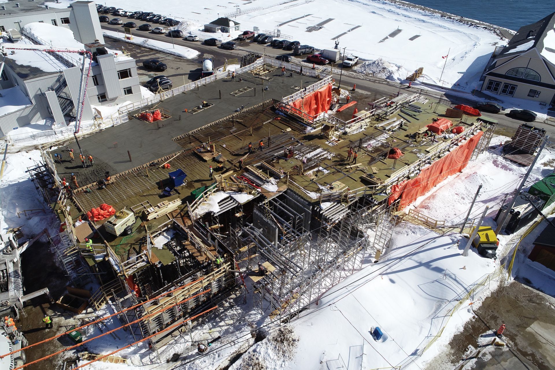 Vue a&eacute;rienne d'un chantier naval avec navire en construction, ouvriers et &eacute;quipements sous la neige.