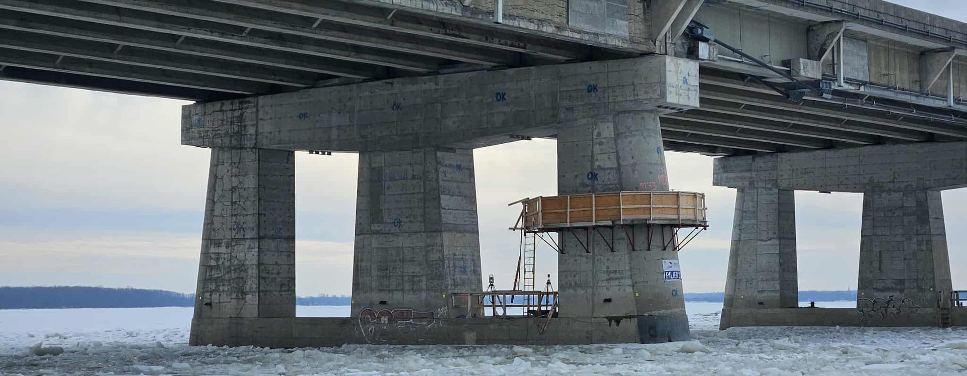 Pont au-dessus de l'eau avec un ouvrier sur un échafaudage autour d'une colonne de soutien centrale