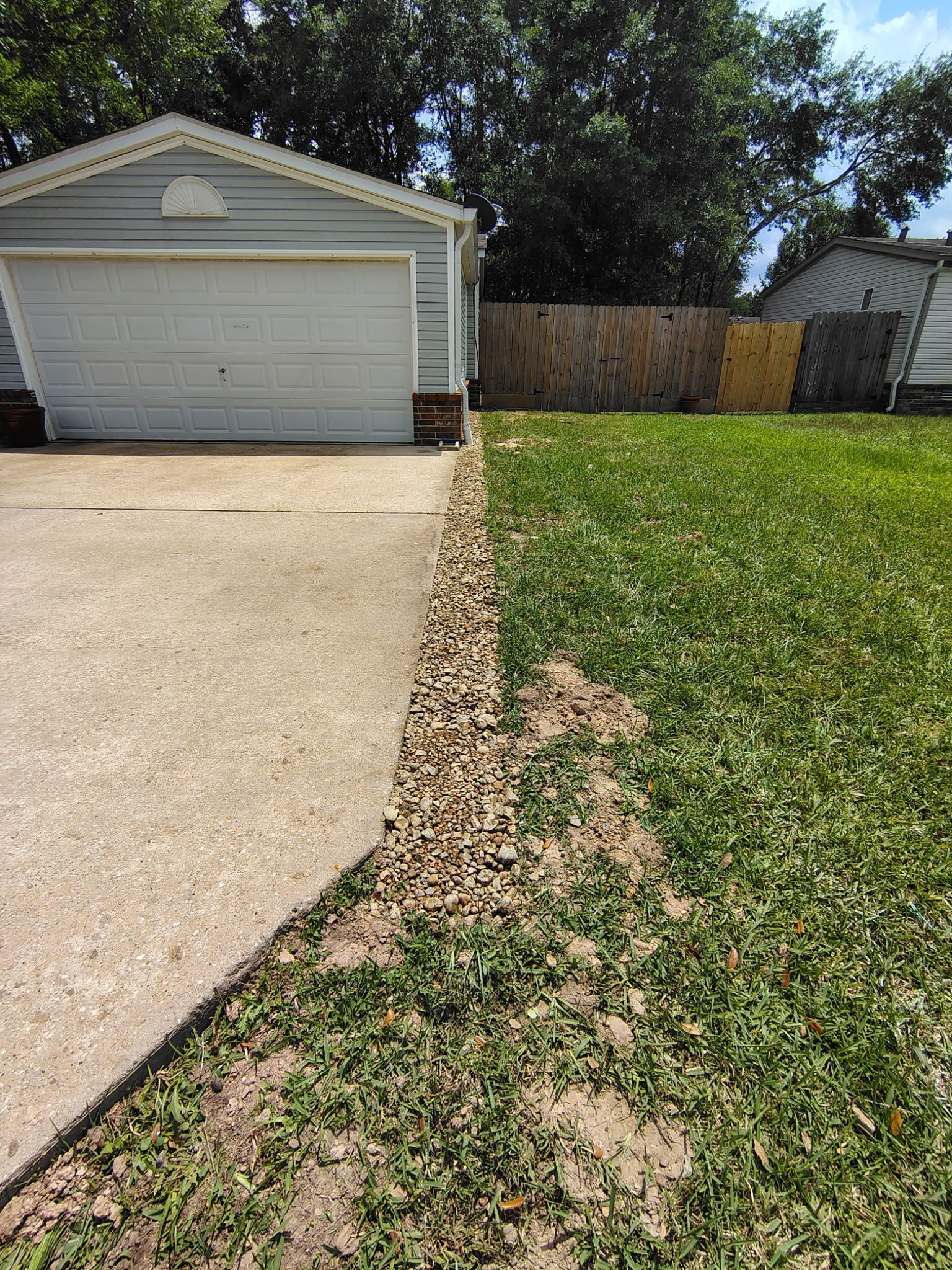 Garage with a concrete driveway and a gravel border along the edge of the lawn.