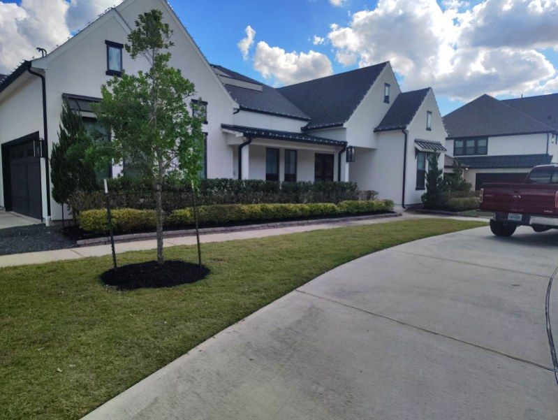 White house with black trim, driveway, green lawn, red truck, and partly cloudy sky.