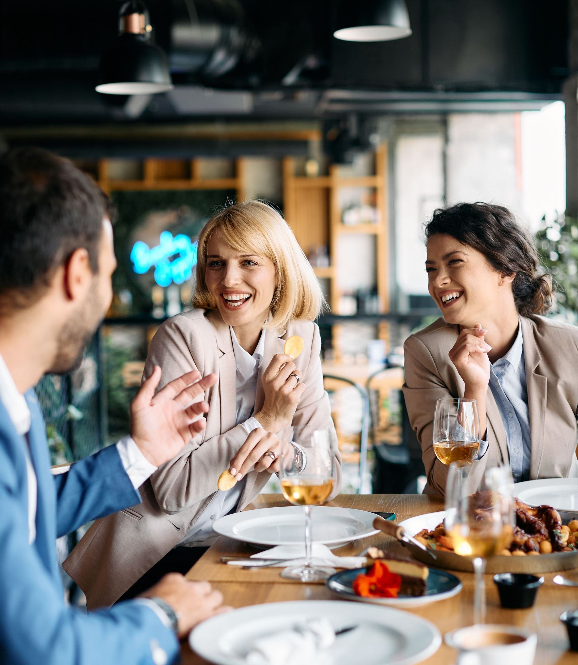 A group of people are sitting at a table eating food and drinking wine.