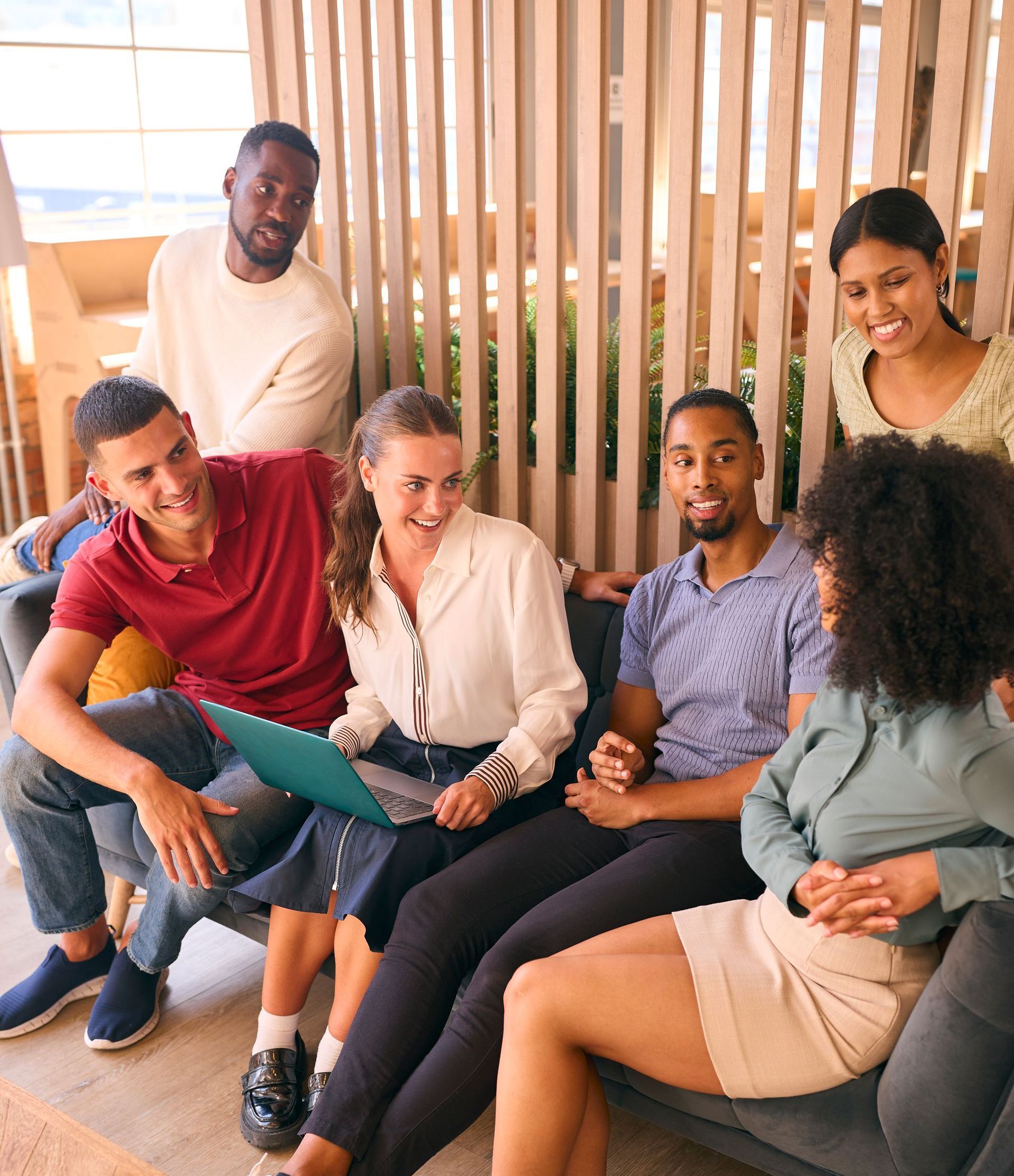 A group of people are sitting on a couch looking at a laptop.