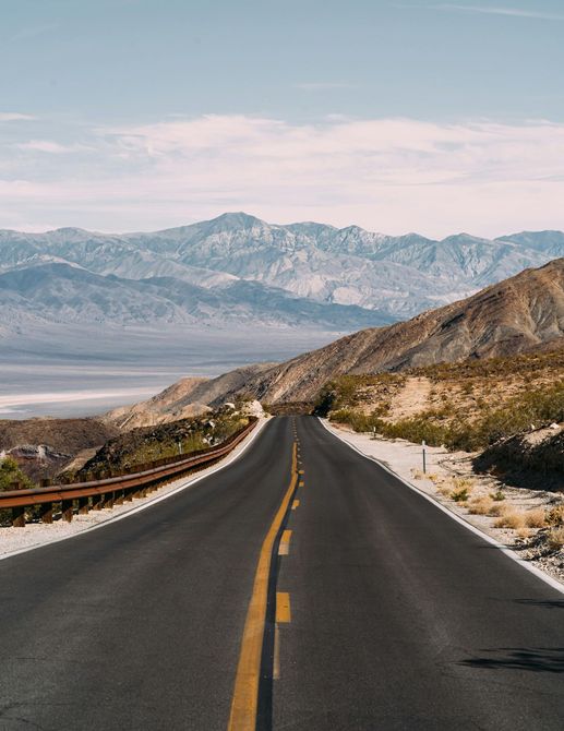 A road going through a desert with mountains in the background.