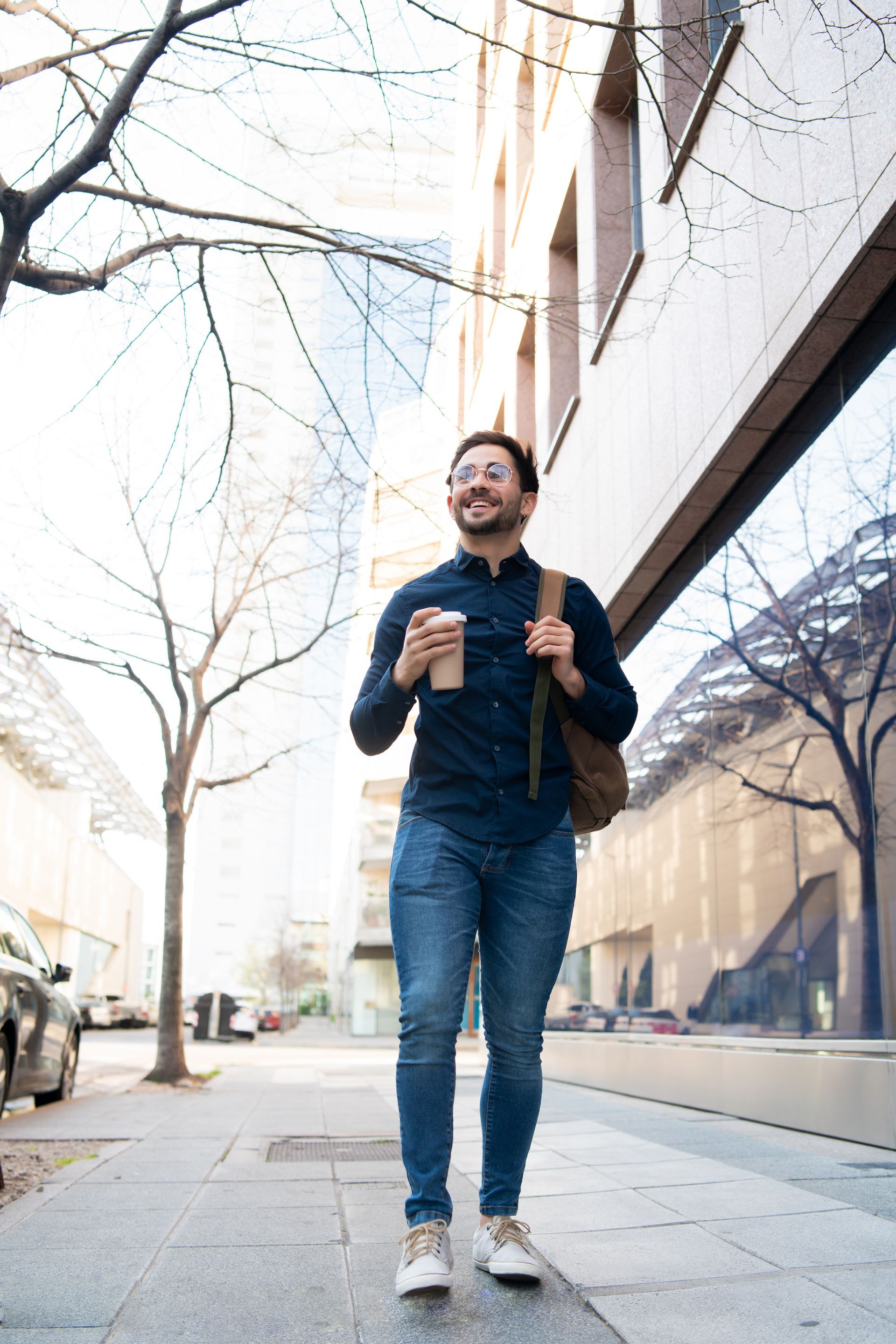 A man is walking down a sidewalk holding a cup of coffee.