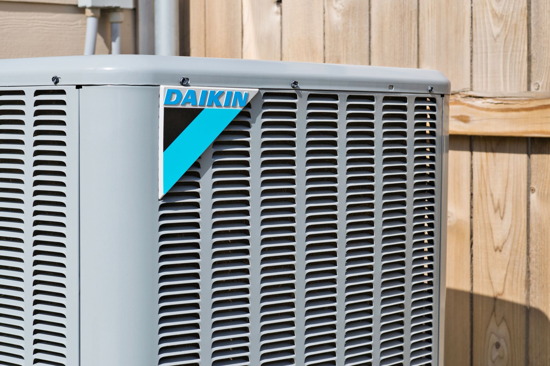 A Daikin Air Conditioner is Sitting Next to a Wooden Fence