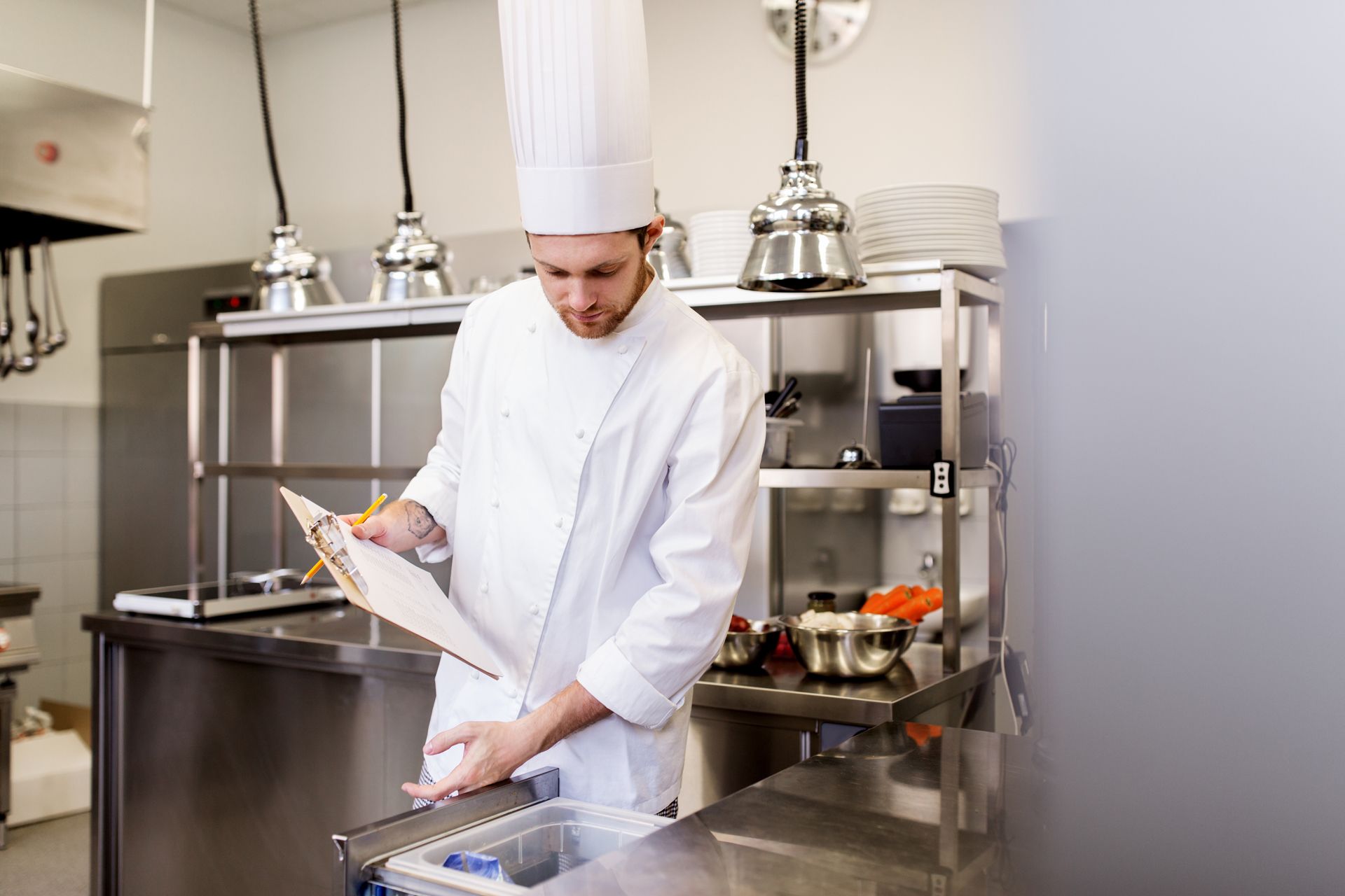 Chef Cook With Clipboard Doing Inventory of Restaurant Kitchen Fridge