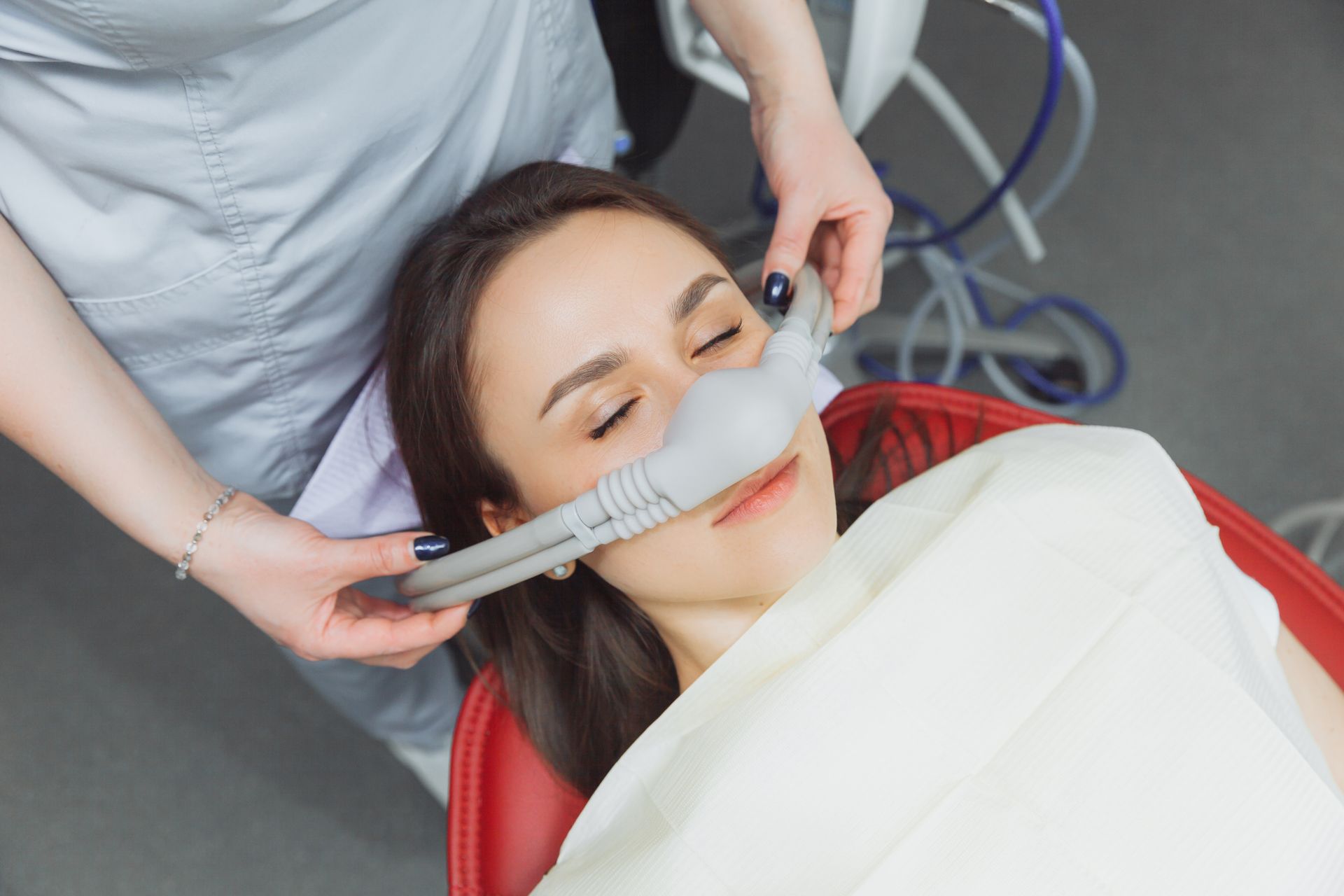 A woman is laying in a dental chair with an oxygen mask on her face.