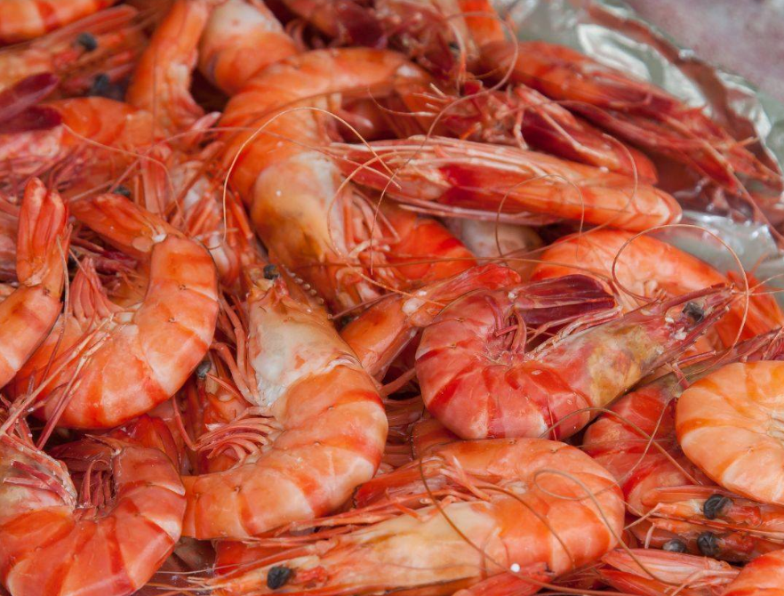 Gamberi cotti ammucchiati con guscio arancione e lunghi baffi su un vassoio