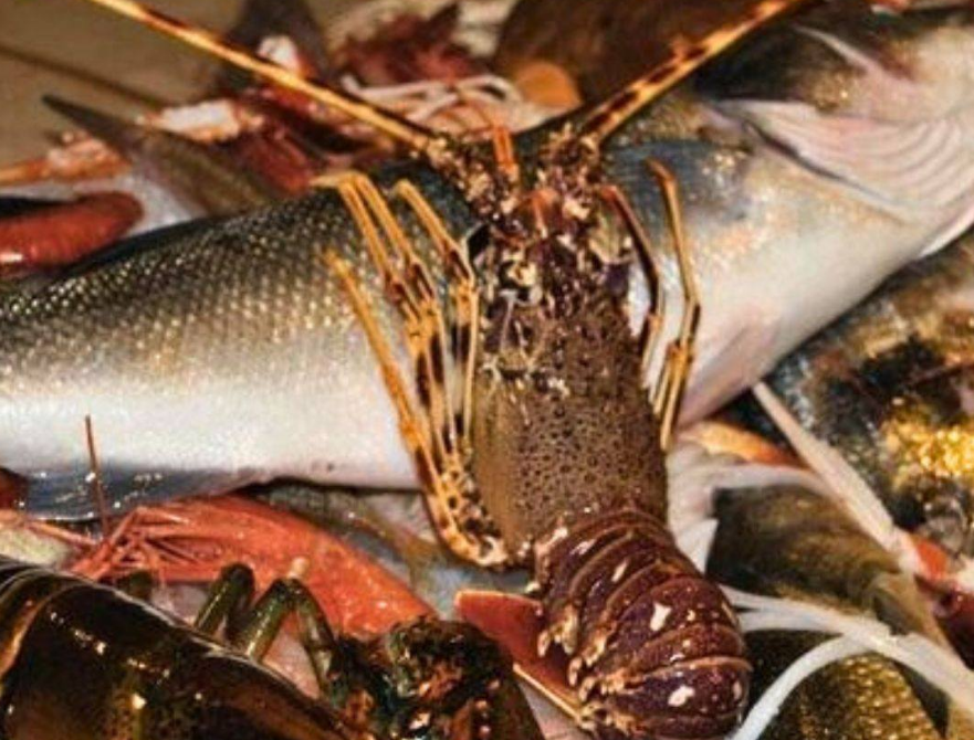 Un'aragosta su un mucchio di pesce fresco e frutti di mare in un mercato del pesce.