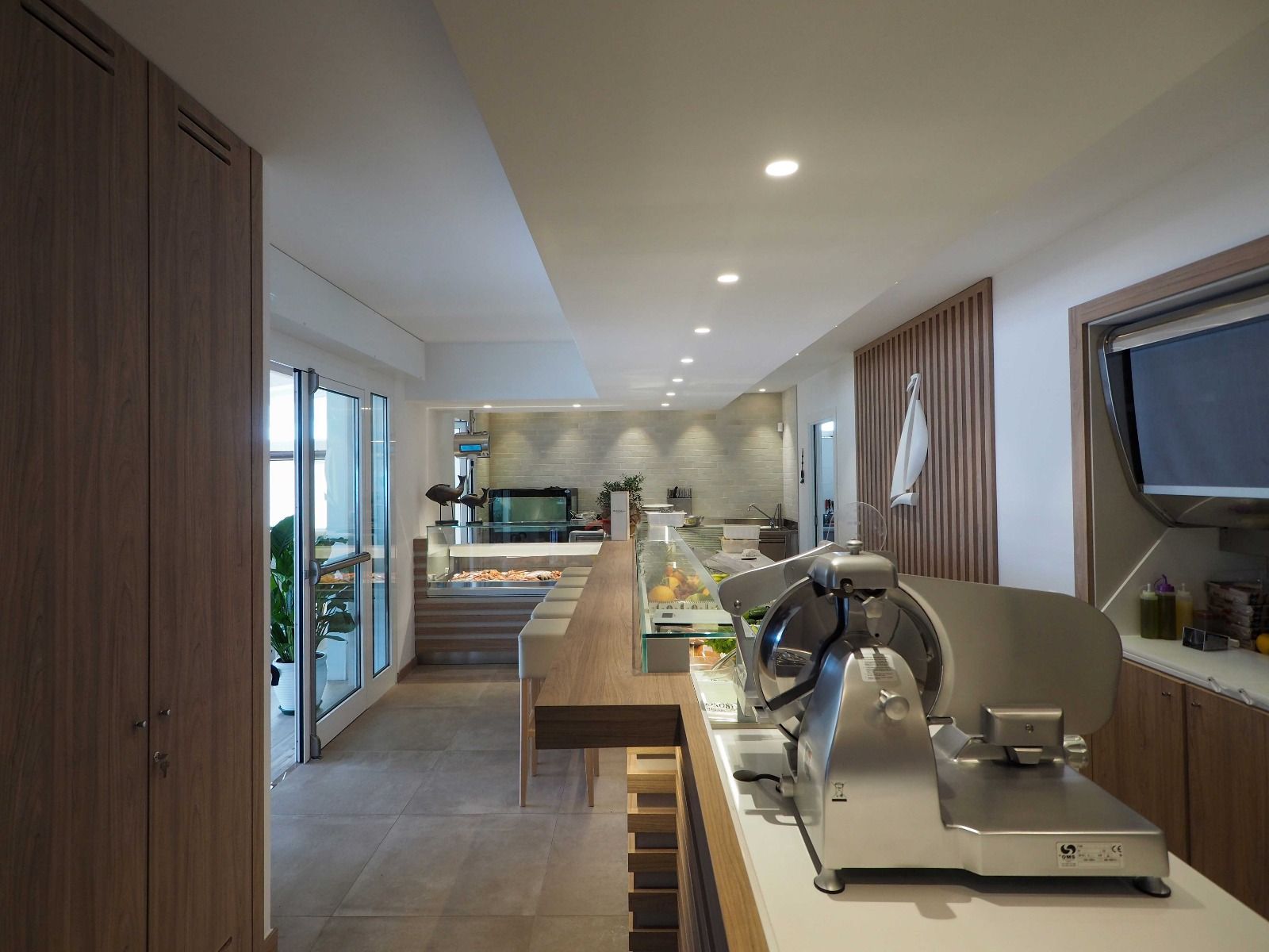 Interni di cucina moderna con isola centrale, mobili in legno e faretti a incasso a soffitto.