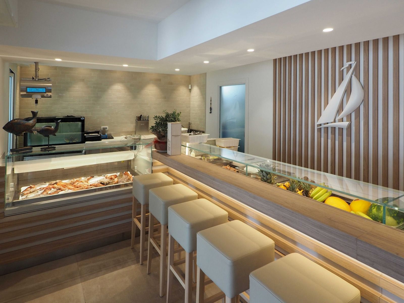 Bancone da caffè moderno con sgabelli, pasticcini, frutta e un elegante interno bianco.