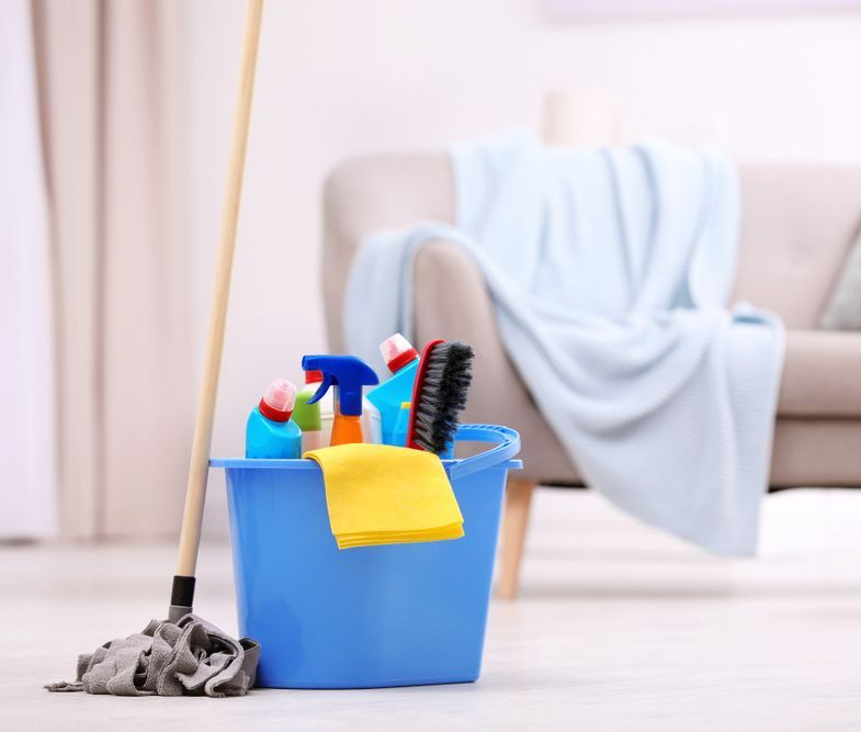 Blue Bucket Filled With Cleaning Supplies and a Mop in a Living Room — Happy Housekeepers in Kootingal, NSW