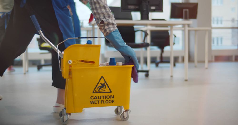 Person is Standing Next to a Yellow Mop Bucket in an Office — Happy Housekeepers in Gunnedah, NSW