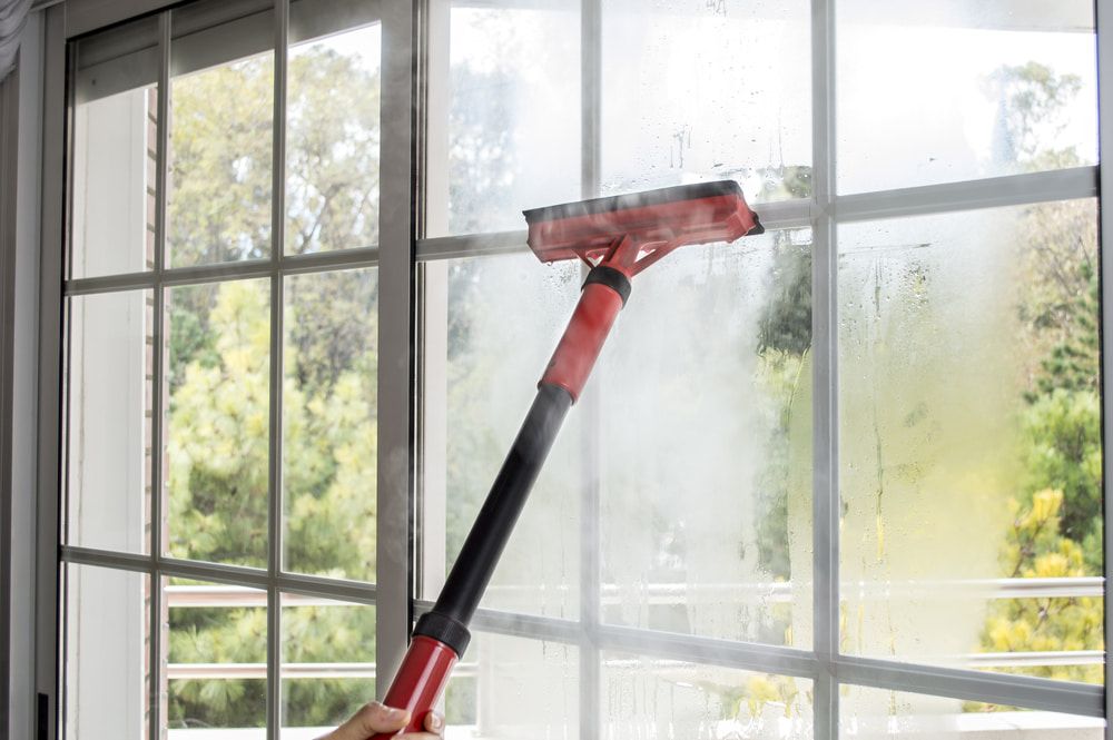 Person is Cleaning a Window With a Steam Cleaner — Happy Housekeepers in South Tamworth, NSW