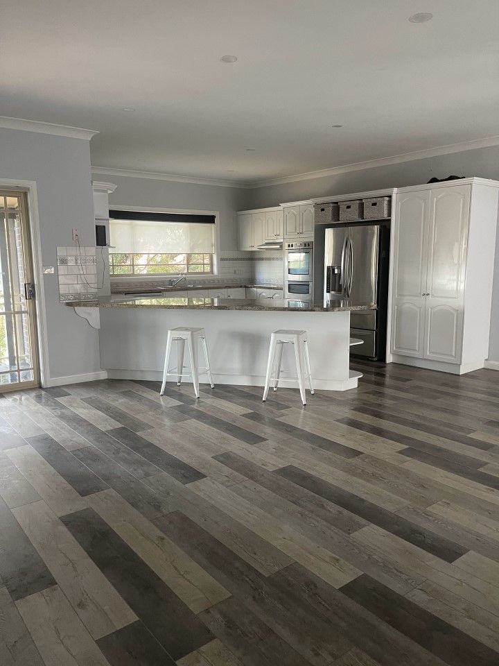 Kitchen With a Wooden Floor and White Cabinets and Stools — Happy Housekeepers in South Tamworth, NSW
